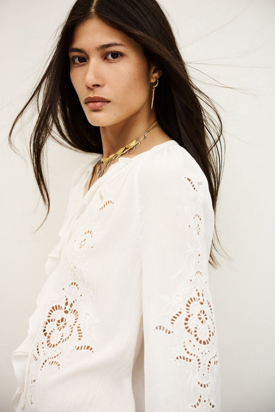 Romantisk ba&sh Omar bluse i ecru med flæser, V-udskæring og broderie anglaise. Lavet i blød viskose og bomuld fra ansvarlige kilder.