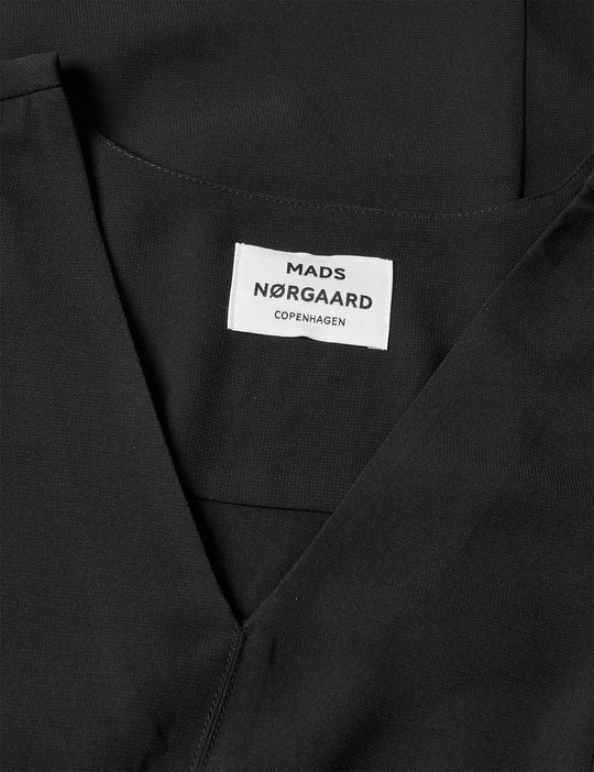 Mads Nørgaard Light Crepe Margot Dress i black. Løs kjole i genanvendt polyester med V-udskæring og korte ærmer.