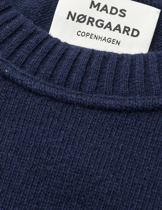 Mads Nørgaard Yota Knit Tilona Sweater i Parisian Night. Boxy strik med spejlvendt logo, fremstillet i uld og genanvendte materialer. Stilfuld og bæredygtig.