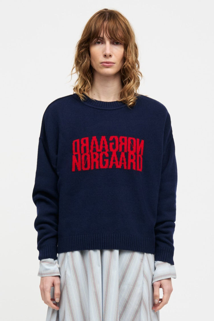 Mads Nørgaard Yota Knit Tilona Sweater i Parisian Night. Boxy strik med spejlvendt logo, fremstillet i uld og genanvendte materialer. Stilfuld og bæredygtig.