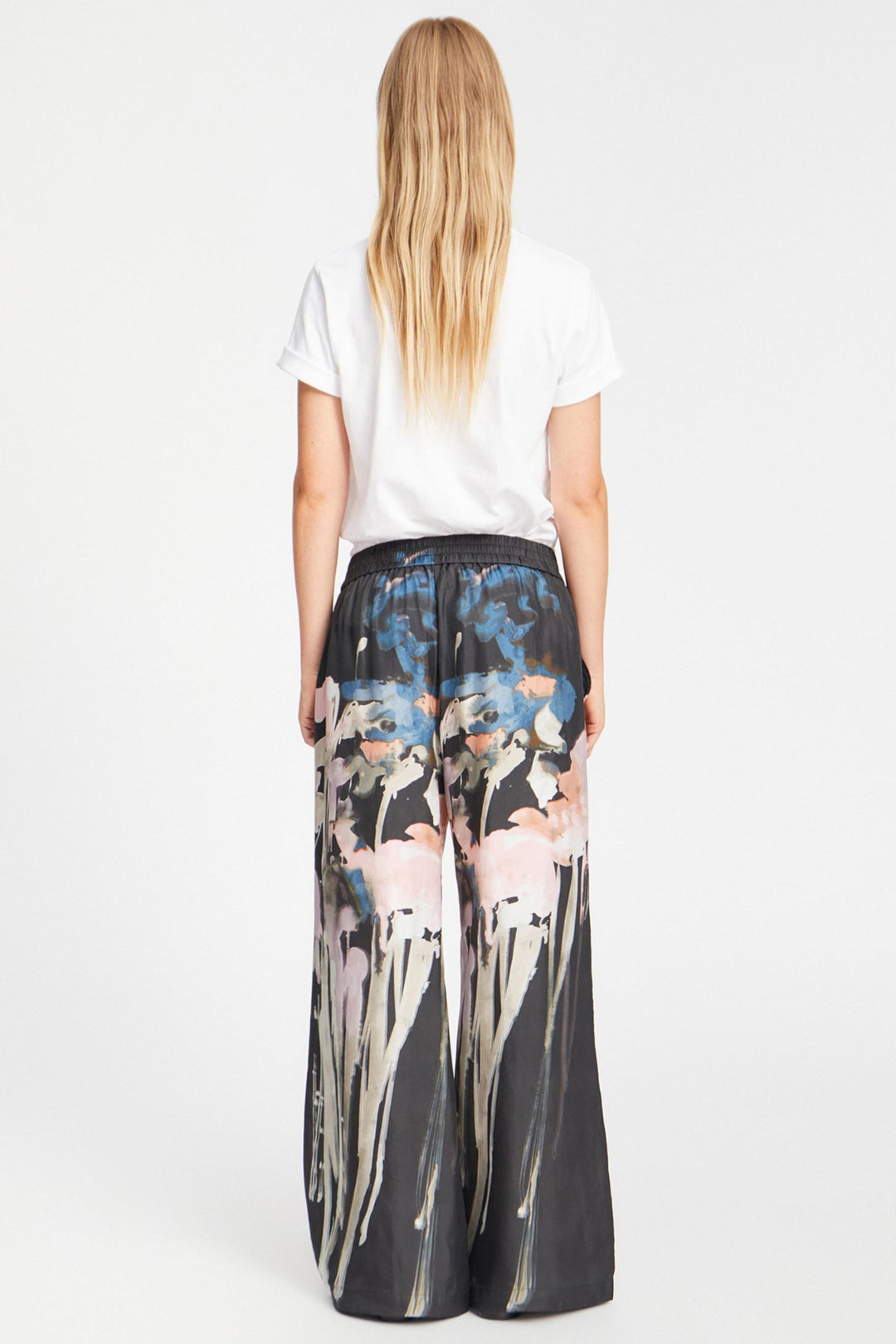 Munthe Arum Silk Pants i sort med et kunstprint – elegante silkebukser med løs pasform, elastik i taljen og sidelommer.