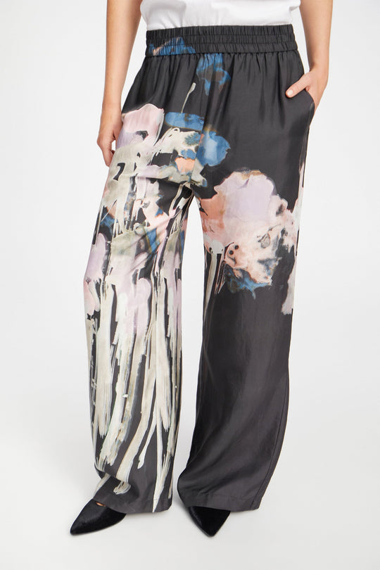 Munthe Arum Silk Pants i sort med et kunstprint – elegante silkebukser med løs pasform, elastik i taljen og sidelommer.