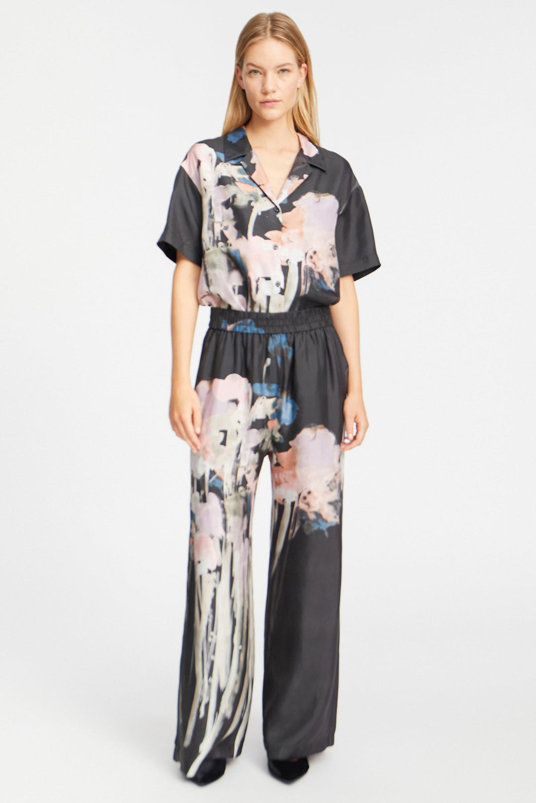 Munthe Arum Silk Pants i sort med et kunstprint – elegante silkebukser med løs pasform, elastik i taljen og sidelommer.