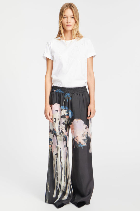 Munthe Arum Silk Pants i sort med et kunstprint – elegante silkebukser med løs pasform, elastik i taljen og sidelommer.