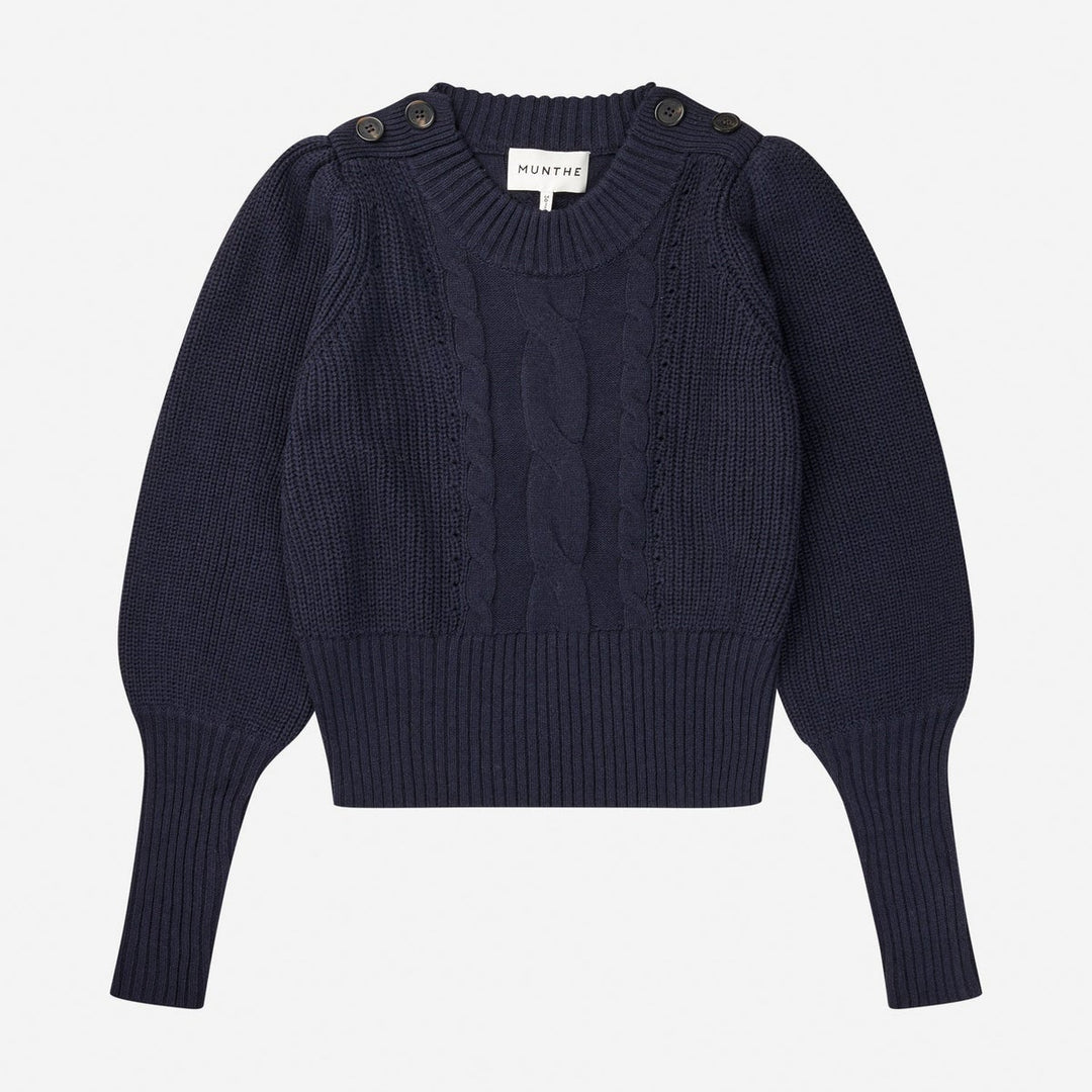 Munthe Lysta navy kabelstrik med brede ærmer, høj ribkant og knaplukning ved halsen. Blød blanding af bomuld, akryl og uld.
