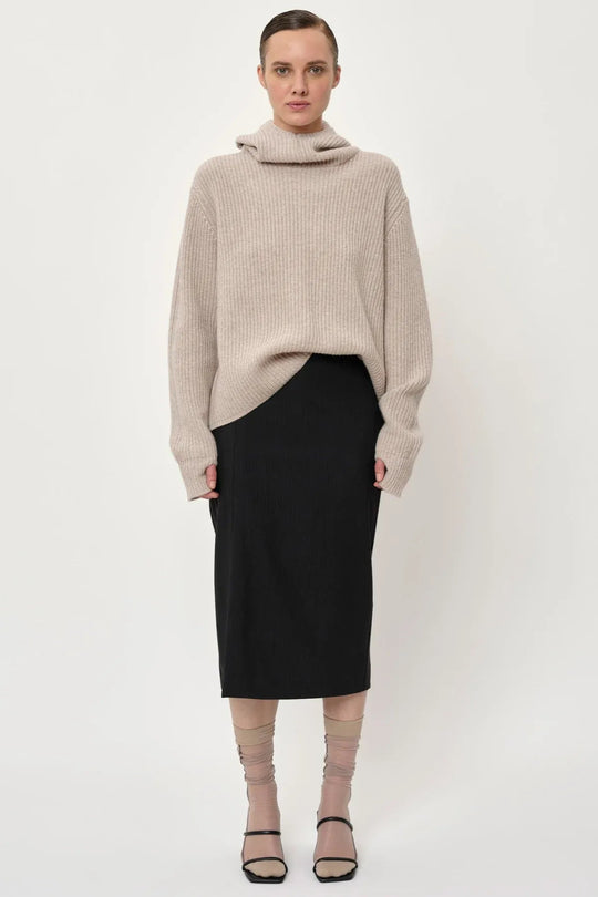 Herskind Mate Skirt – mellemlang nederdel i mørkegrå pinstripe med elegant sideslids. Perfekt pasform og tidløst design.