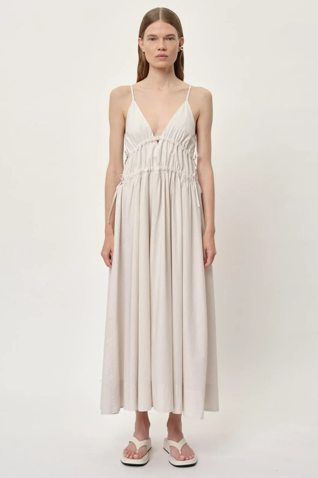 Herskind Miranda Dress i creme pinstripe – lang V-hals kjole med horisontale cutlines og justerbar snøre.