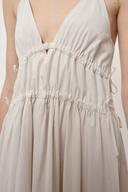 Herskind Miranda Dress i creme pinstripe – lang V-hals kjole med horisontale cutlines og justerbar snøre.