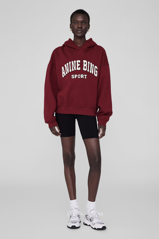 Anine Bing Alec Hoodie Sport i cabernet rød. Chenille patch i ivori og sort broderi. Let oversized pasform med kortere længde for en afslappet, sporty stil.