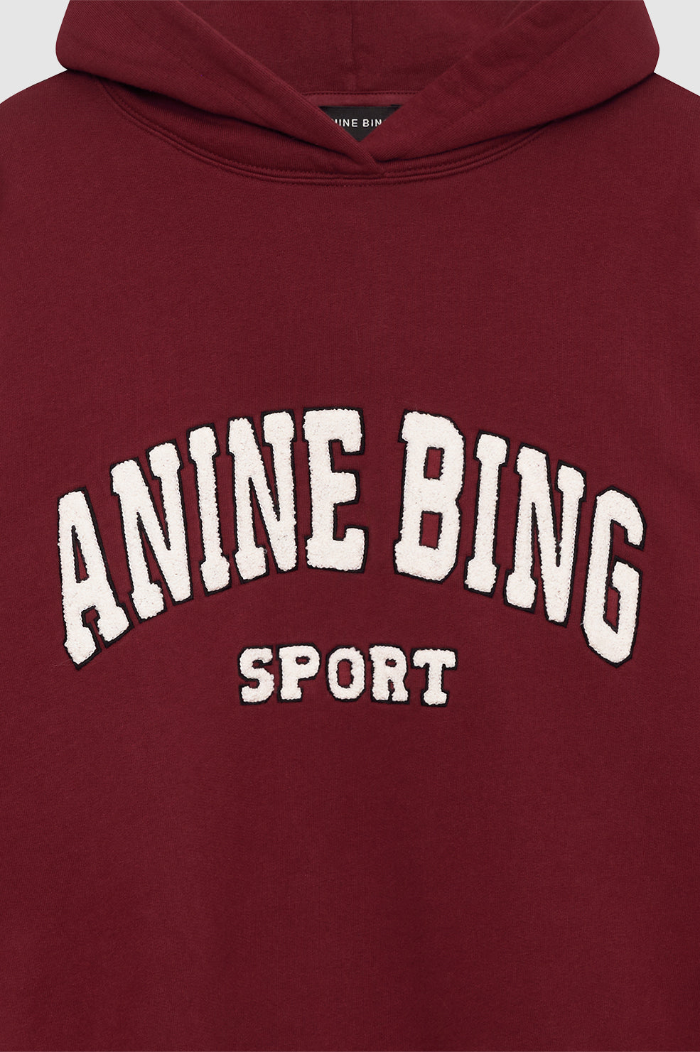 Anine Bing Alec Hoodie Sport i cabernet rød. Chenille patch i ivori og sort broderi. Let oversized pasform med kortere længde for en afslappet, sporty stil.