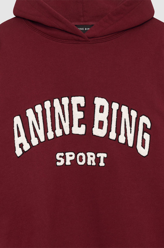Anine Bing Alec Hoodie Sport i cabernet rød. Chenille patch i ivori og sort broderi. Let oversized pasform med kortere længde for en afslappet, sporty stil.