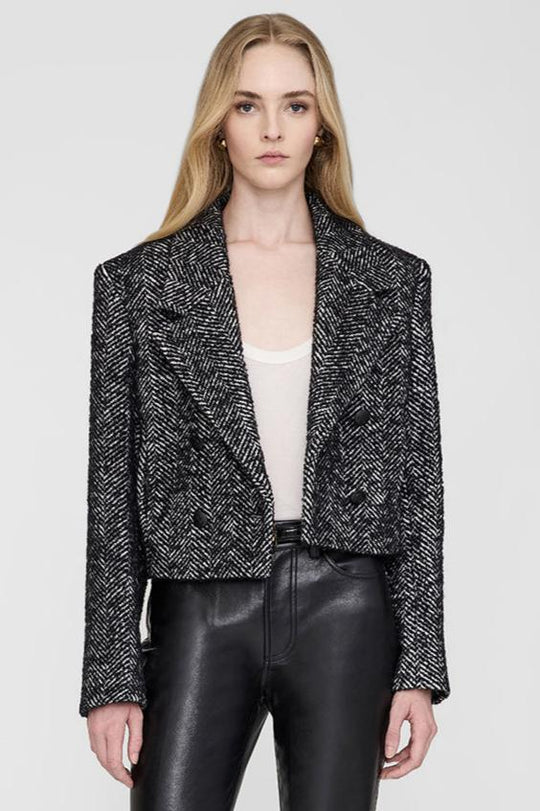 Anine Bing Vienna Blazer i sort og hvid tweed med herringbone-mønster. Cropped snit, dobbeltradet lukning og sofistikerede detaljer for et elegant look.