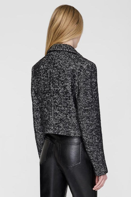 Anine Bing Vienna Blazer i sort og hvid tweed med herringbone-mønster. Cropped snit, dobbeltradet lukning og sofistikerede detaljer for et elegant look.