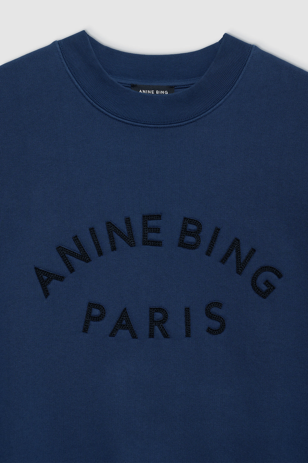 Anine Bing Jaci Paris sweatshirt i washed navy med oversized pasform, vintage-inspireret filtpatch og 100 % bomuldsfleece. Eksklusivt og komfortabelt design.