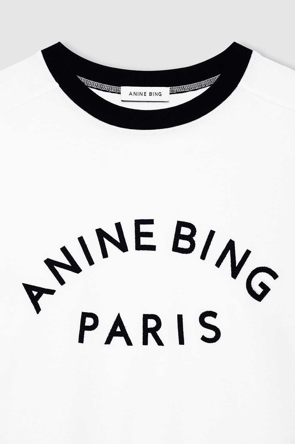 Anine Bing Jaylin Tee Paris i ivory med sorte kontrastdetaljer, boxy fit og filtpatch. Lavet i kraftig 100 % bomuldsjersey – tidløs og cool.