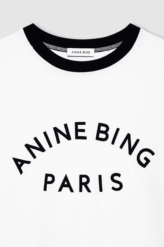 Anine Bing Jaylin Tee Paris i ivory med sorte kontrastdetaljer, boxy fit og filtpatch. Lavet i kraftig 100 % bomuldsjersey – tidløs og cool.