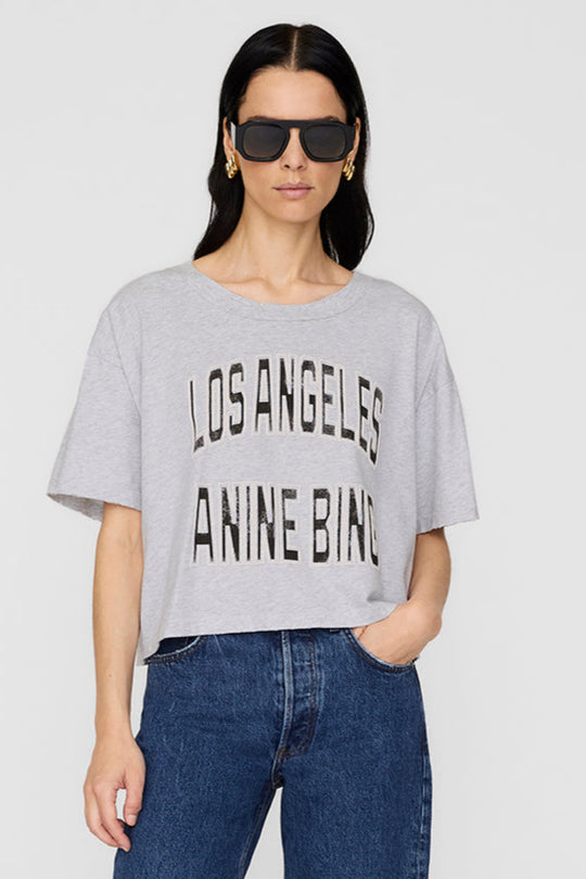 Johnny Cropped Tee fra Anine Bing – grå T-shirt med vintage LA-print og rå detaljer. Cropped pasform og 100% bomuld.