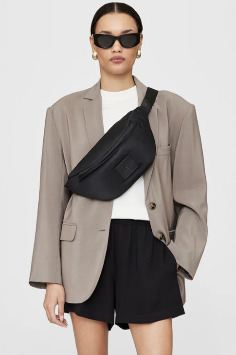 Anine Bing Leon Waist Bag i sort nylon med justerbar rem og lynlåslukkede rum. En moderne, praktisk taske med eksklusive læderdetaljer.