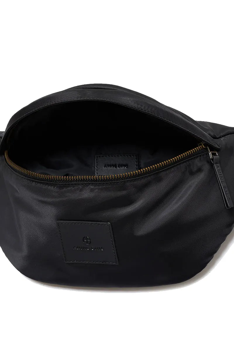 Anine Bing Leon Waist Bag i sort nylon med justerbar rem og lynlåslukkede rum. En moderne, praktisk taske med eksklusive læderdetaljer.