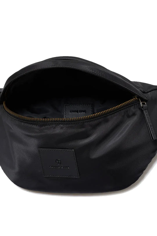 Anine Bing Leon Waist Bag i sort nylon med justerbar rem og lynlåslukkede rum. En moderne, praktisk taske med eksklusive læderdetaljer.