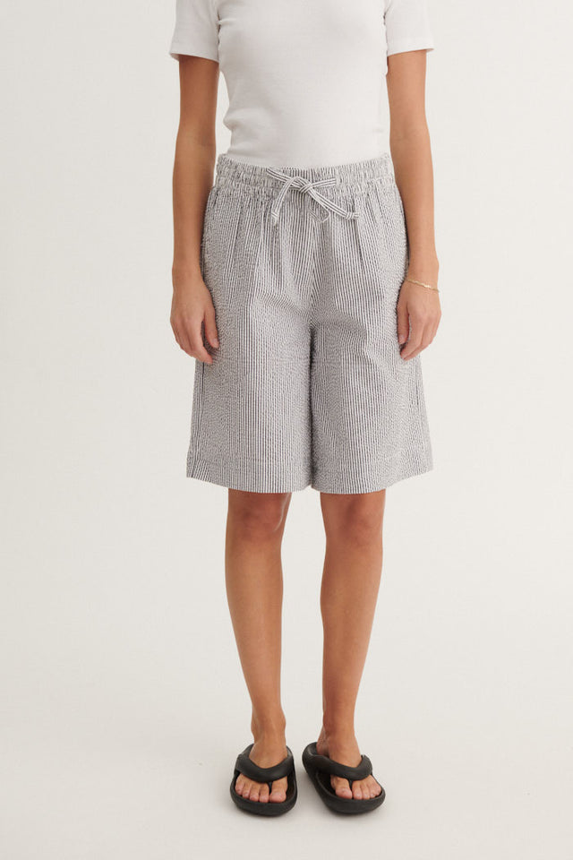 Basic Apparel Asta Shorts i økologisk bomuld med blå-hvide striber, elastik i taljen, bindebånd og knælængde. Regular fit og bæredygtigt design.