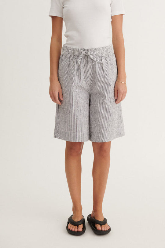 Basic Apparel Asta Shorts i økologisk bomuld med blå-hvide striber, elastik i taljen, bindebånd og knælængde. Regular fit og bæredygtigt design.