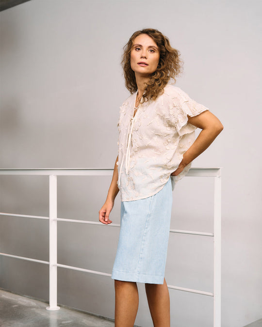 La Rouge Britt Blouse i let bomuld med 3D-blomster, flæseærmer og V-udskæring. Feminin og luftig sommerbluse i creme.