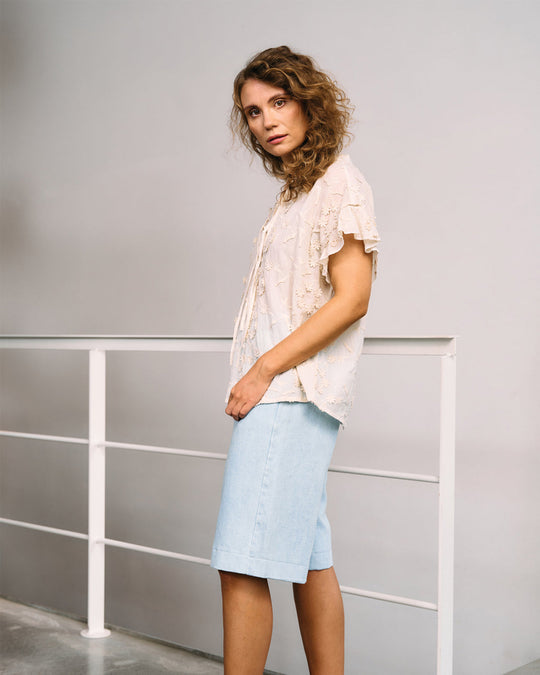 La Rouge Britt Blouse i let bomuld med 3D-blomster, flæseærmer og V-udskæring. Feminin og luftig sommerbluse i creme.