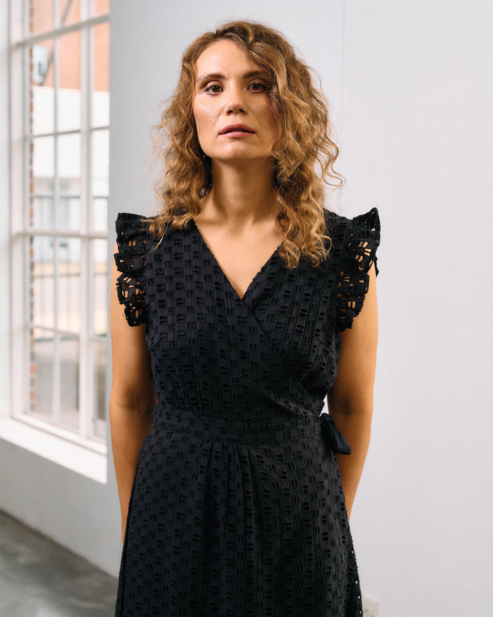 Sort slå-om kjole fra La Rouge i 100% bomuld med broderi anglaise, V-udskæring og bundflæse.