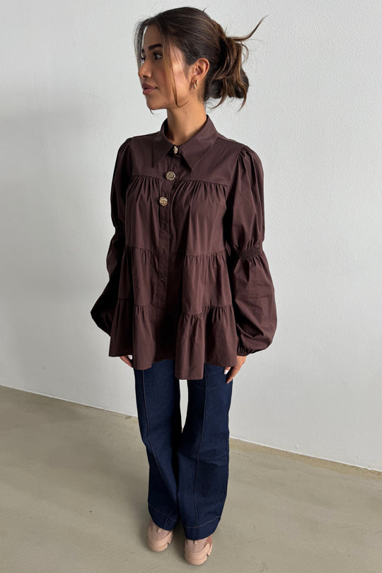 Continue Sanna Gold Buttons skjorte i dark brown – mørkebrun skjorte med guldknapper, flæser, pufærmer og løs pasform.
