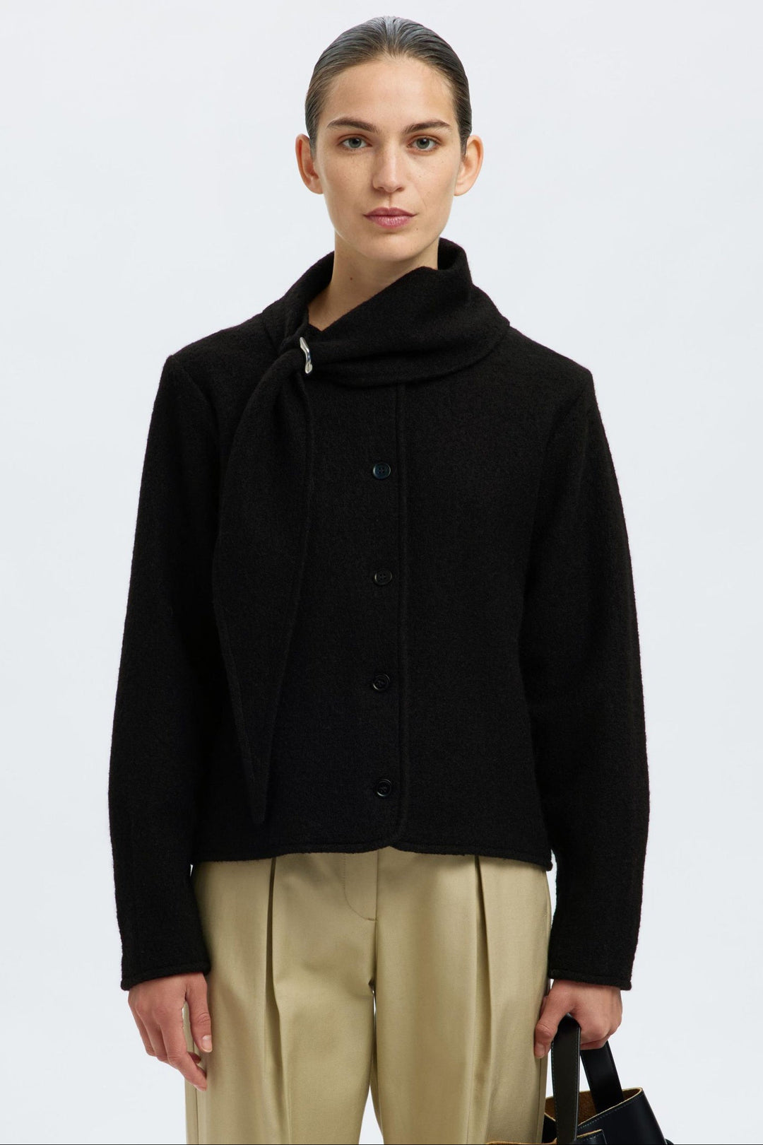 Selected Femme Darla LS Knit Jacket i sort med krave, metalspænde, knaplukning og lange ærmer i 100% uld.
