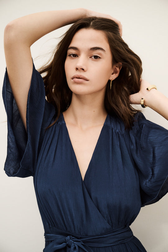 ba&sh Natalia Dress i mørk blå – elegant plisseret maxi kjole i dark blue med wrap-neck og bælte i taljen. Perfekt til sommerens events.