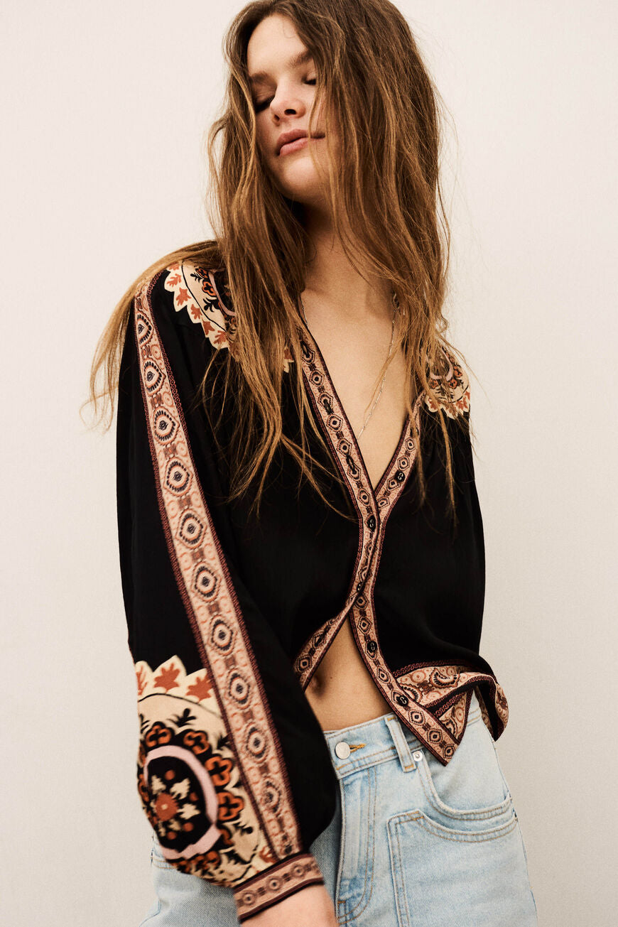 ba&sh Valda Shirt i carbone – løstsiddende mønstret skjorte med roset-applikationer, klassisk krave og let puffede lange ærmer.
