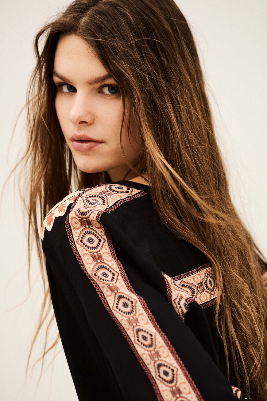 ba&sh Valda Shirt i carbone – løstsiddende mønstret skjorte med roset-applikationer, klassisk krave og let puffede lange ærmer.
