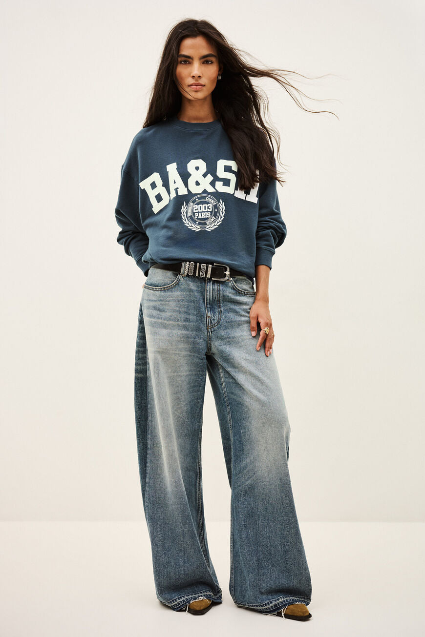 Benjamin sweatshirt i bleu med løs pasform, kort længde og college-inspireret logo. Lavet i økologisk bomuld med stræk. 