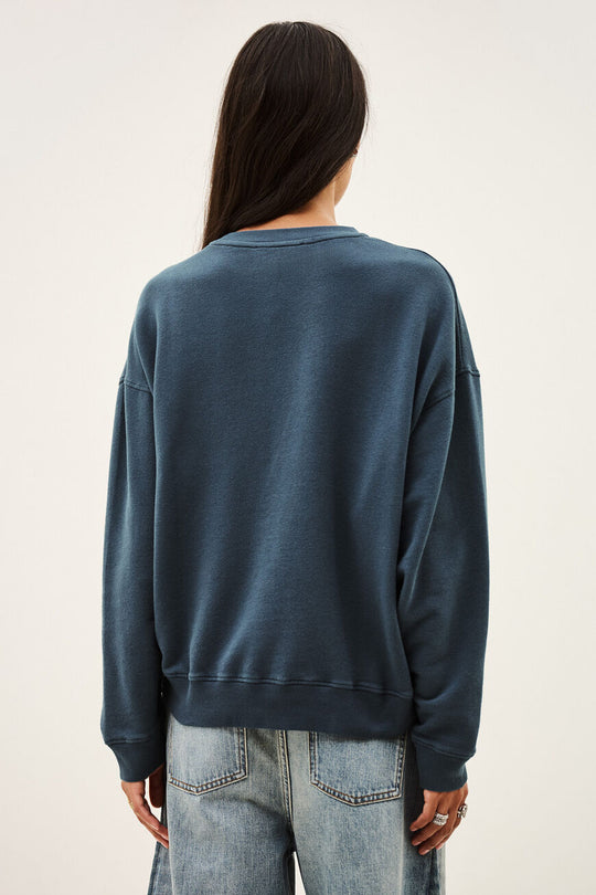 Benjamin sweatshirt i bleu med løs pasform, kort længde og college-inspireret logo. Lavet i økologisk bomuld med stræk. 
