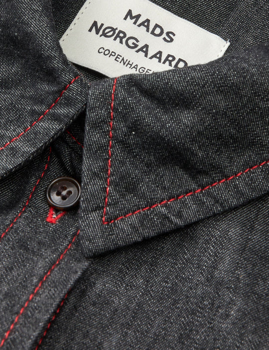Mads Nørgaard Air Denim Crissy skjortekjole i sort med rød kontrastsyning. Let denim i 65 % økologisk bomuld. Knælang med klassiske detaljer. 