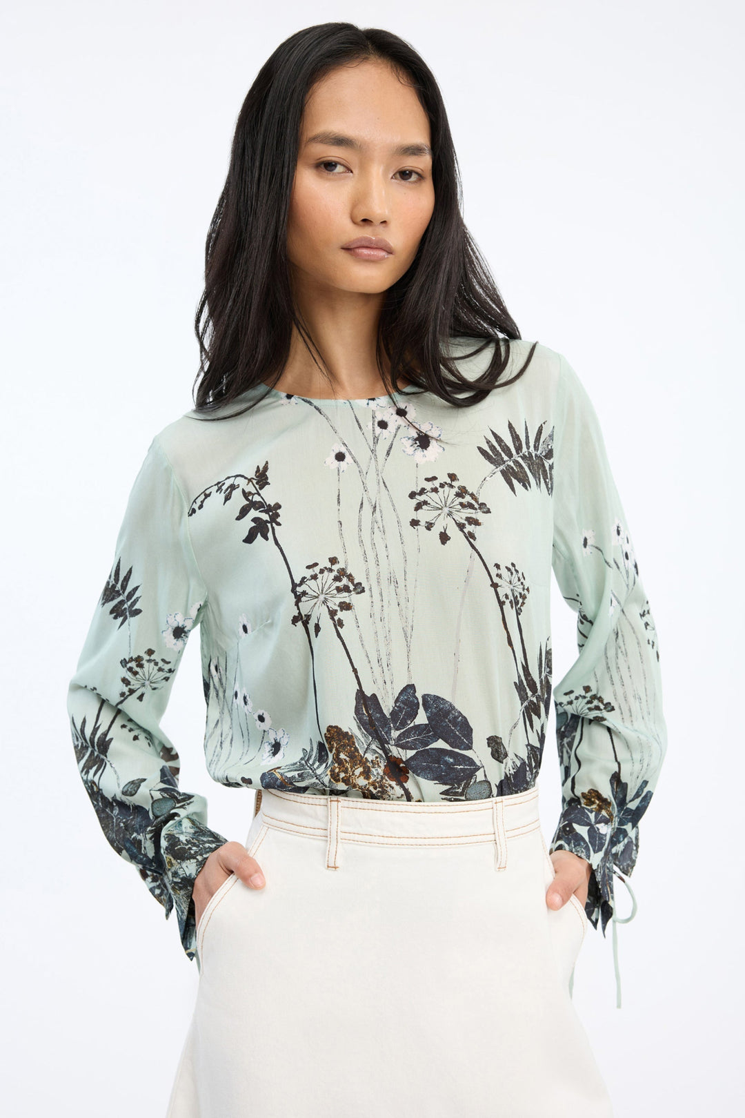 Munthe Basilia Top – Mint. Top med flerfarvet botanisk print, rund hals med bindedetalje og lange ærmer med bånd ved håndleddene.
