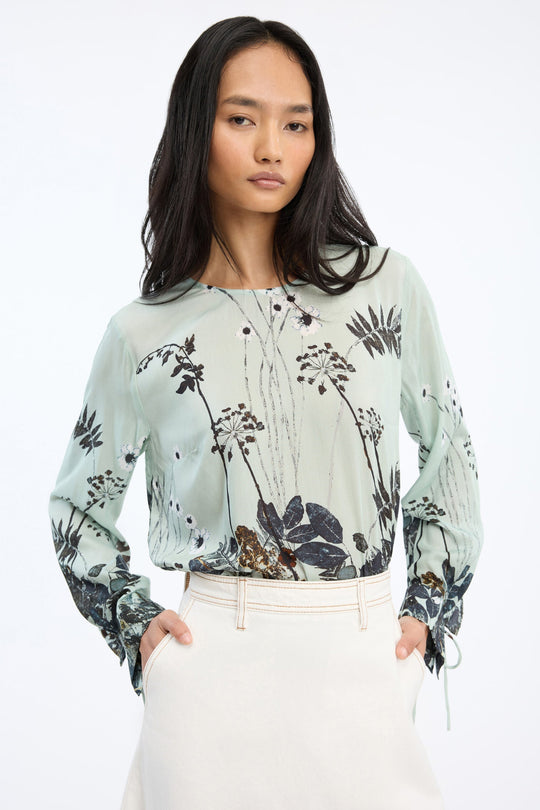 Munthe Basilia Top – Mint. Top med flerfarvet botanisk print, rund hals med bindedetalje og lange ærmer med bånd ved håndleddene.
