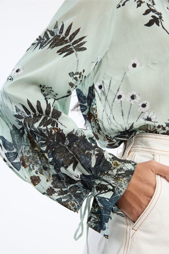 Munthe Basilia Top – Mint. Top med flerfarvet botanisk print, rund hals med bindedetalje og lange ærmer med bånd ved håndleddene.
