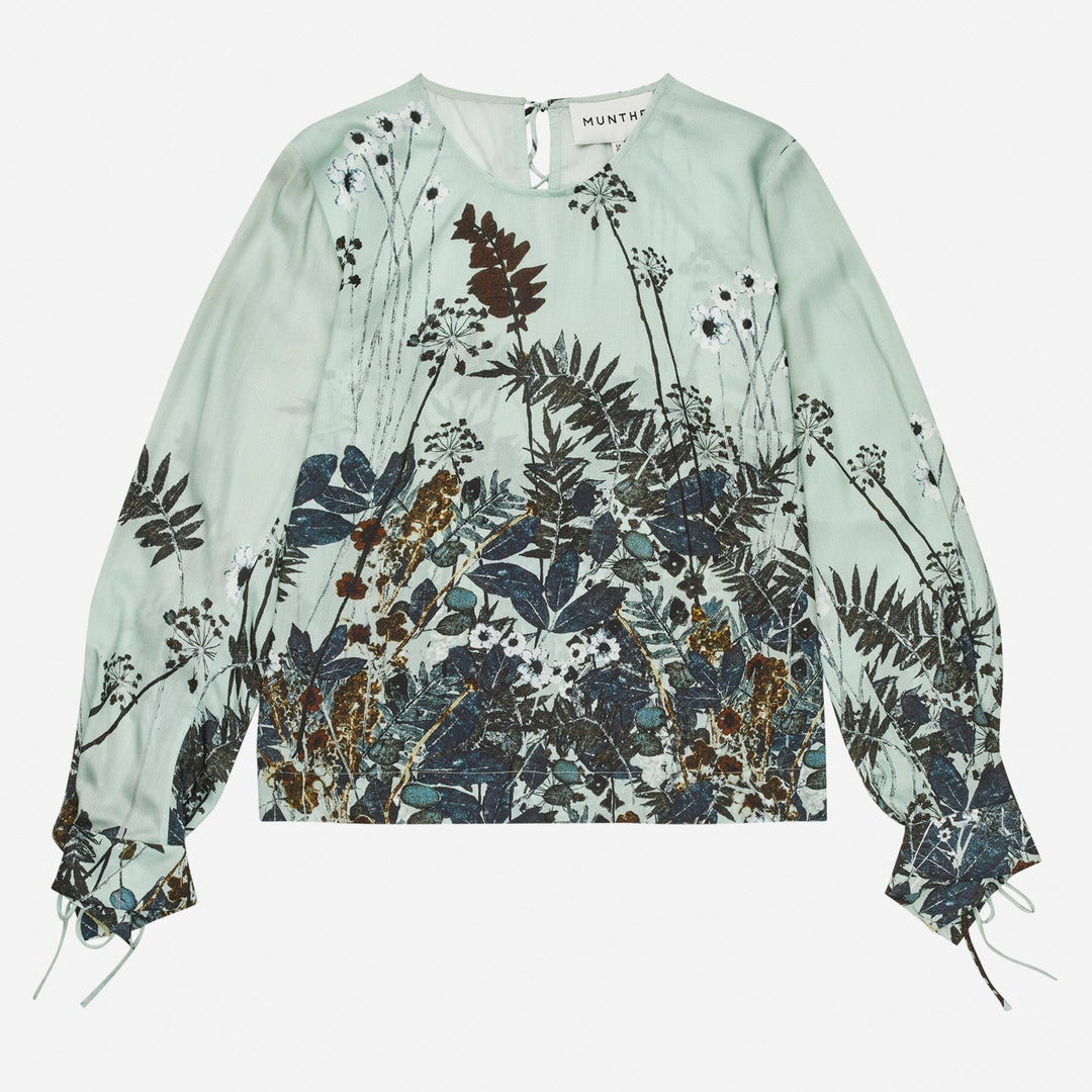 Munthe Basilia Top – Mint. Top med flerfarvet botanisk print, rund hals med bindedetalje og lange ærmer med bånd ved håndleddene.
