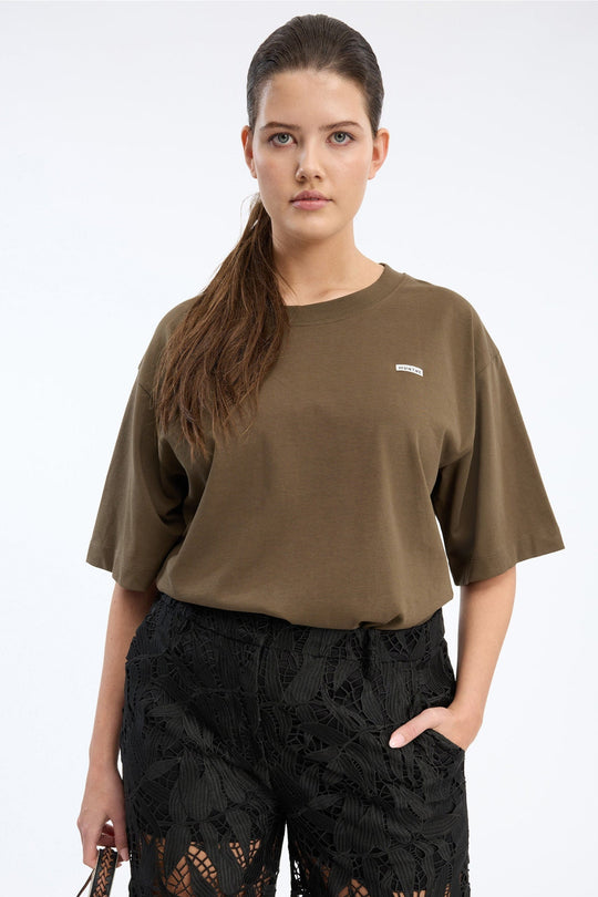 Munthe Bellamy Jersey – Brown. Cropped t-shirt med rund hals, korte ærmer og diskret MUNTHE-logo i blød jersey.
