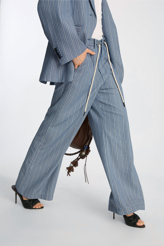 Munthe Bobey Pants – Blue. Bukser med bred benprofil, justerbart bindebånd i taljen, front- og baglommer og løs pasform.
