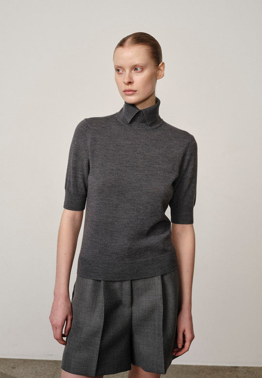 Perry Knit Blouse Grey – merinoudstrik med høj krave, taljelængde og gråt, rent look.
