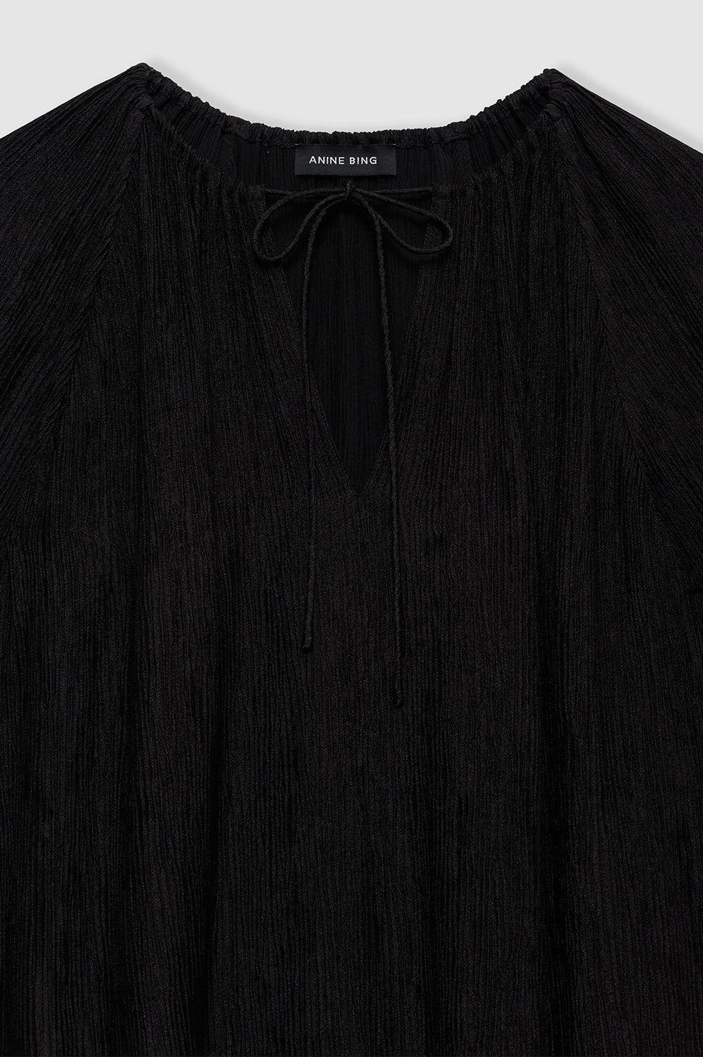 Anine Bing Lolita Dress – en elegant sort minikjole i plisseret strik med justerbar bindedetalje. 