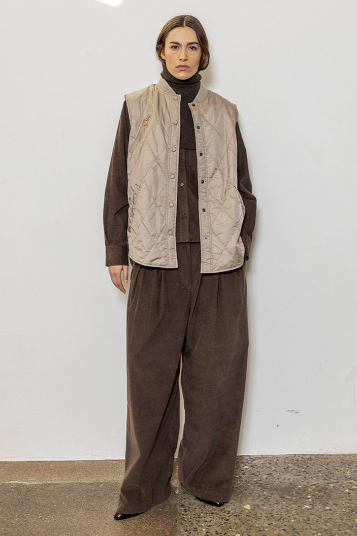 Project AJ117 Tailor Bukser i Coffee – brede bukser i blød baby-corduroy med for-pliéer, stiklommer og klassisk lynlås- og knaplukning. Fremstillet i 100% økologisk bomuld.
