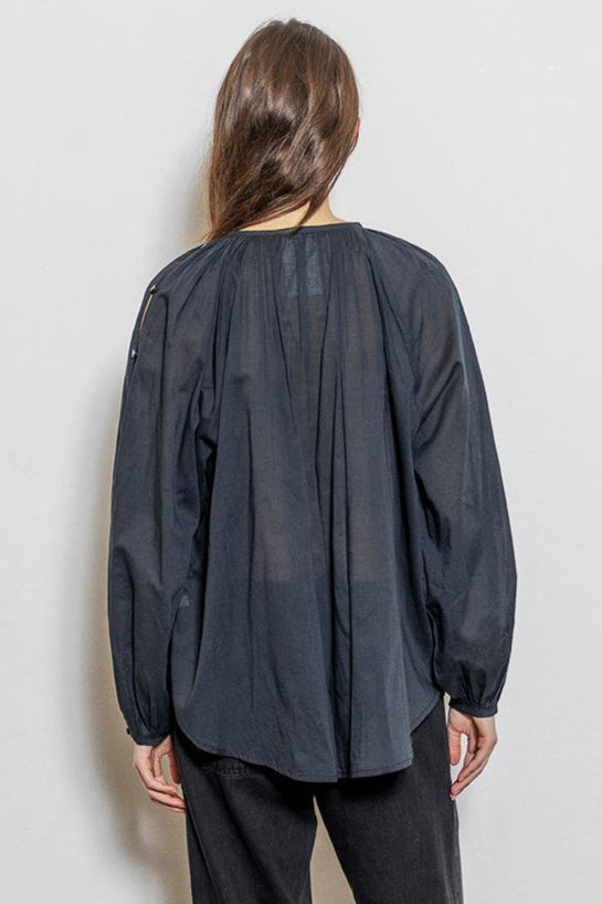 Project AJ117 Hester Bluse i Black – feminin skjorte med gathered hals, raglanærmer, dekorative knapper og afrundet kant, fremstillet i 100% økologisk bomuldsvoile.

