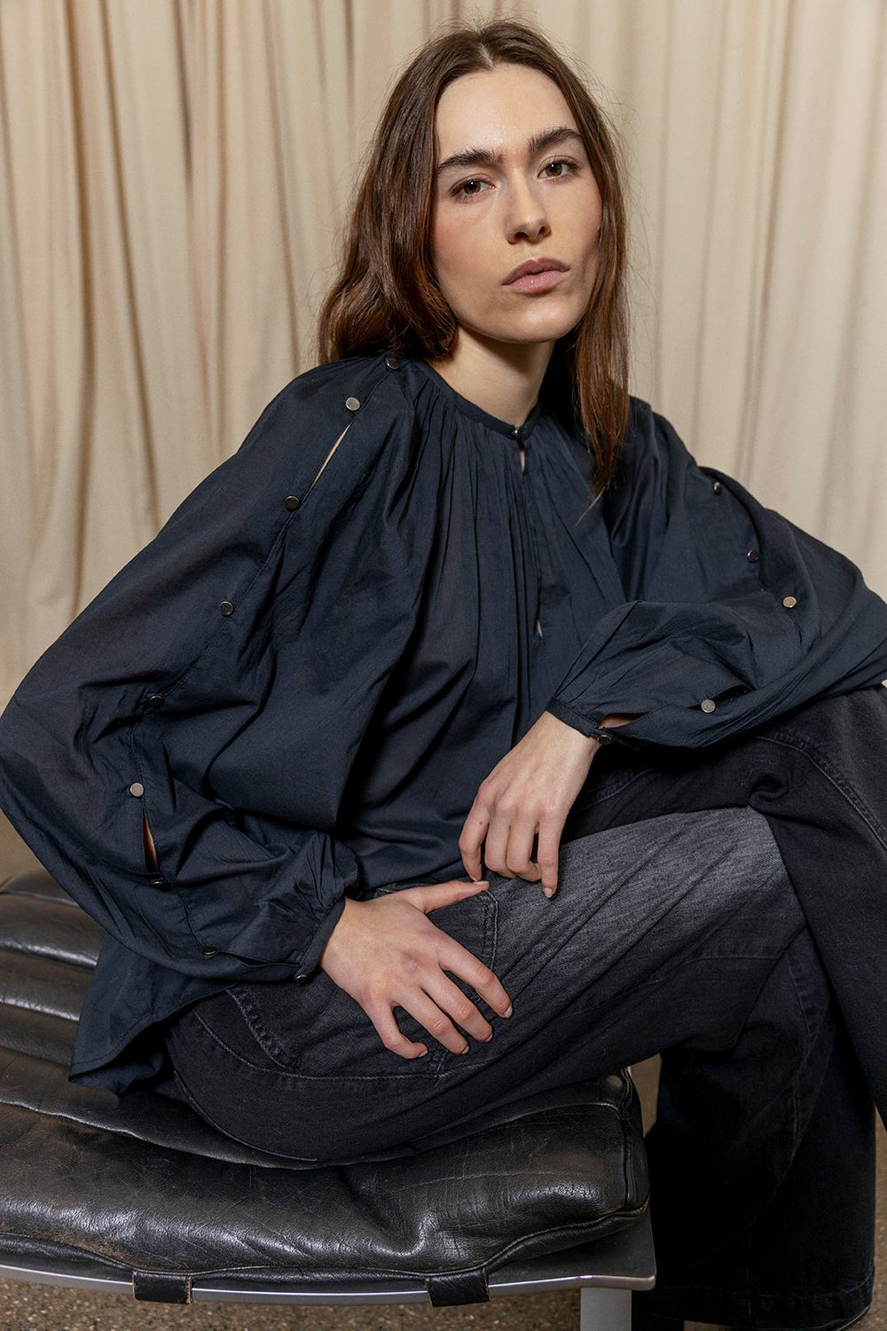 Project AJ117 Hester Bluse i Black – feminin skjorte med gathered hals, raglanærmer, dekorative knapper og afrundet kant, fremstillet i 100% økologisk bomuldsvoile.
