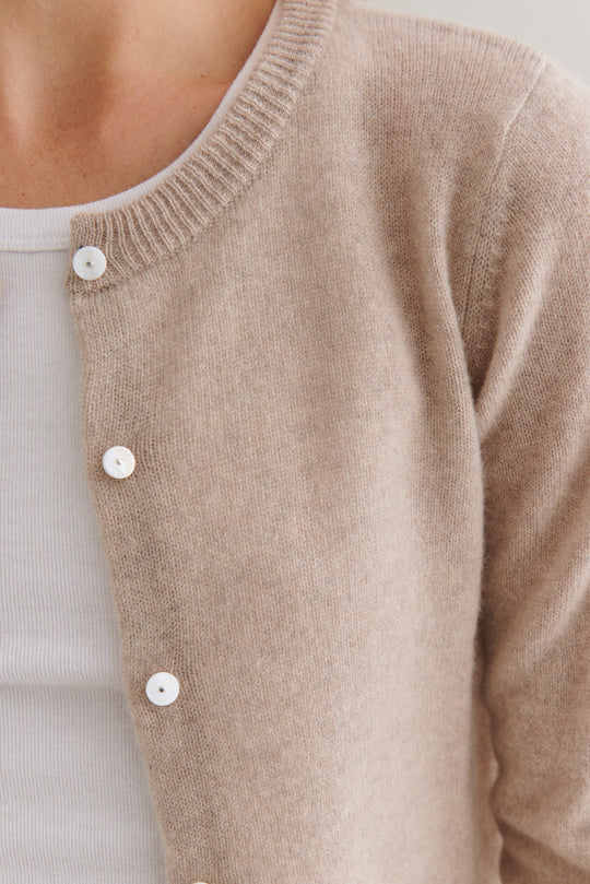 Beta Studios Classic Cardigan Cashmere i sand melange – klassisk langærmet cashmere-cardigan med ribkanter og perlemorsknapper, lavet i 100% cashmere. 
