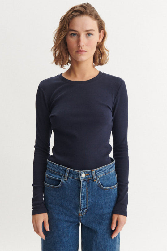 Basic Apparel Ludmilla LS Tee i sky captain – tætsiddende bluse i økologisk bomuld med ribstruktur, lange ærmer og afrundet hals.
